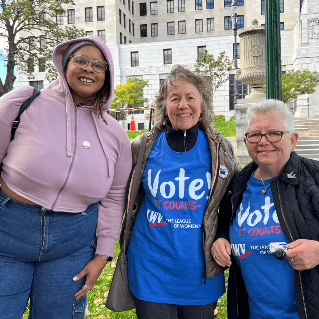Three women in blue t - shirts standing in front of a building.