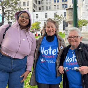 Three women in blue t - shirts standing in front of a building.